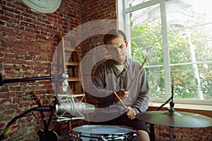 Young man recording music, playing drums and singing at home