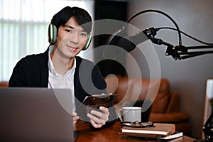 Young man recording a podcast on his laptop computer with headphones and a microphone