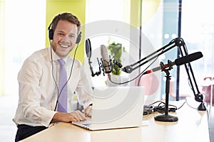 Young man recording a podcast smiling to camera, close up