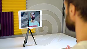 a young man records a video using a teleprompter on a tablet