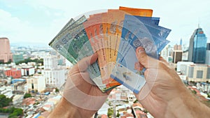 A young man recounts in his hands the money of Malaysia against the background of the city center of Kuala Lumpur. photo