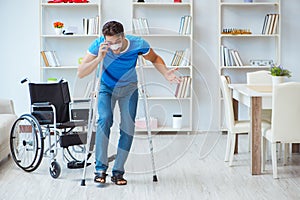 Young man recovering after surgery at home with crutches and a w