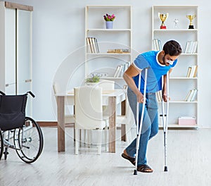 Young man recovering after surgery at home with crutches and a w