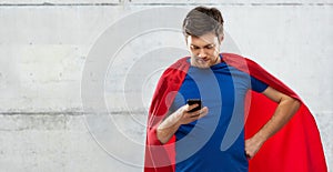 Young man in red superhero cape using smartphone