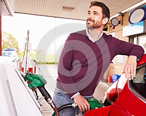 Young man refuelling a car at a petrol station