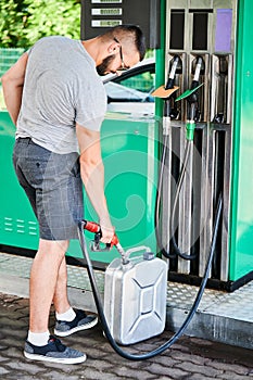 Young man refuling canister with fuel for his stalled automobile.