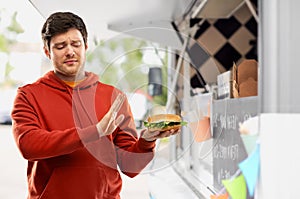 Young man refusing from hamburger at food truck