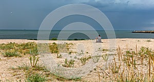 Young man relax siting on the sea beach pier looks straight from sunset sky. Conceptual for thinking and looking to focus on