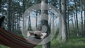 A young man relaxes on a hammock in the forest. Parzen with a beard swings on a hammock. A sleeping young man.