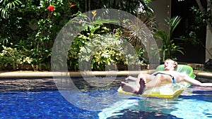 Young man relaxing on air mattress in swimming pool, slow motion. 3840x2160