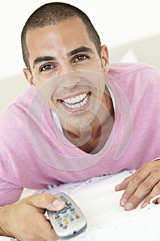 Young Man Relaxing On Bed Watching TV