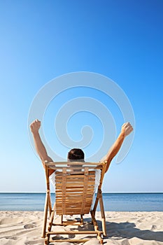 Young man relaxing in  chair on sandy beach