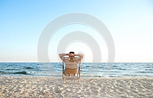 Young man relaxing in deck chair on beach