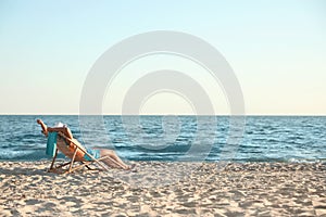 Young man relaxing in deck chair on beach