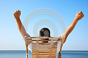 Young man relaxing in deck chair on beach