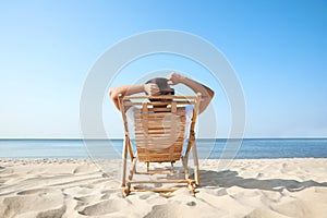 Young man relaxing in deck chair on beach