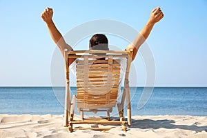 Young man relaxing in deck chair on beach