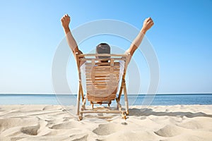 Young man relaxing in deck chair on beach