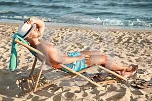 Young man relaxing in deck chair on beach near