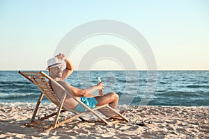 Young man relaxing in deck chair on beach