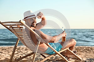 Young man relaxing in deck chair on beach  sea