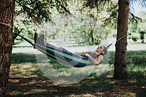 Young man relaxing in a hammock in a sunny park, enjoying peace and solitude outdoors