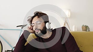 Young man relaxing at home listening to music with headphones