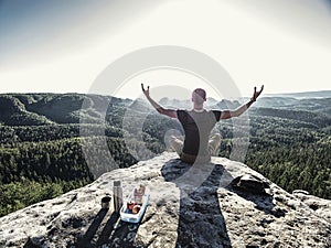 Young man relaxing on rocky cliff. Man sitting on rock point