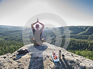 Young man relaxing on rocky cliff. Man sitting on rock point