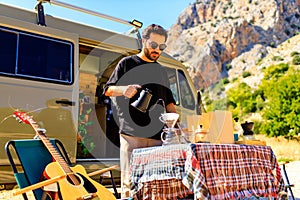 young man relaxing in rv, camping in a trailer mountain background