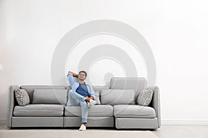 Young man relaxing on sofa against wall