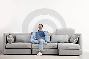 Young man relaxing on sofa against wall