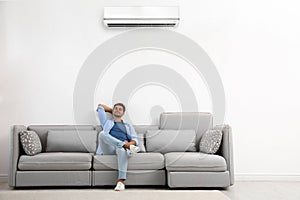 Young man relaxing on sofa against wall