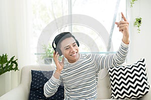 Young man relaxing on sofa with headphones in the living room.