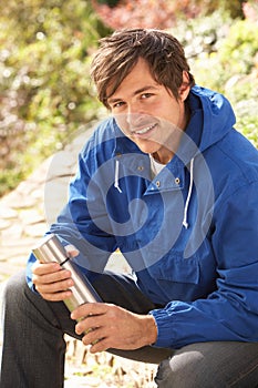 Young Man Relaxing With Thermos Flask In Autumn La photo