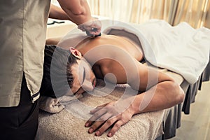 Young man relaxing during traditional massage with hot stones