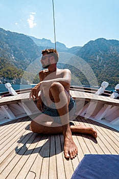 Young man relaxing on a wooden boat during a boat trip to Butterfly beach at Fethiye Turkey, Tanning young boy in swim