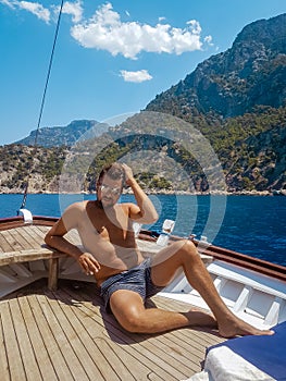 Young man relaxing on a wooden boat during a boat trip to Butterfly beach at Fethiye Turkey, Tanning young boy in swim