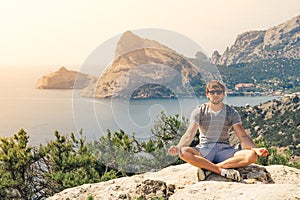 Young Man relaxing yoga on rocky mountains