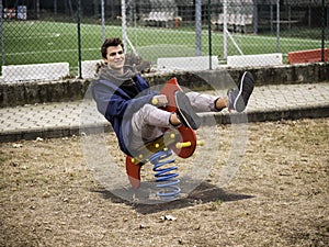 Young man reliving his childhood in a playground