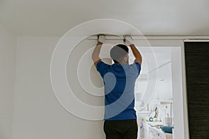 A young man removes the curtain rod.