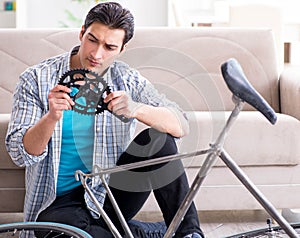 Young man repairing bicycle at home