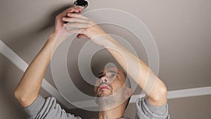 Young man repairing cable wiring and installs or replaces the halogen lamp on the ceiling