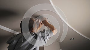 A young man is repairing a ceiling soffit. Replacing the LED lamp at the downlight