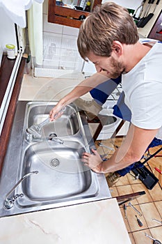 Young man repairing kitchen sink