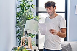 Young man repairing lamp reading instructions at home