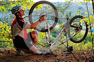 Young man repairing mountain bike in the forest