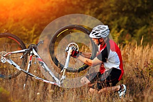 Young man repairing mountain bike in the forest