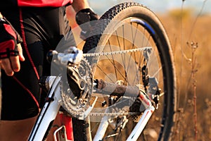 Young man repairing mountain bike in the forest