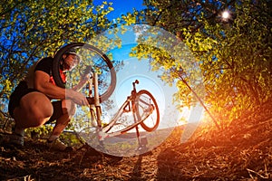 Young man repairing mountain bike in the forest